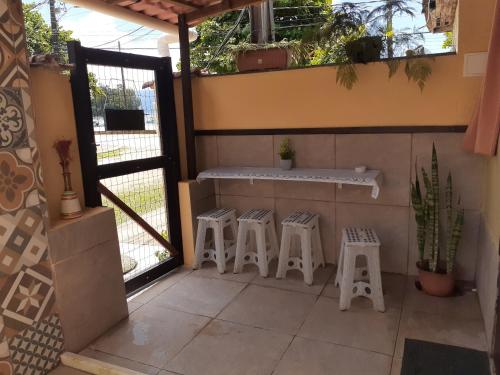 a patio with three stools and a counter with a window at Suíte da Vila - Beira Mar in Abraão