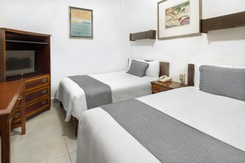 a hotel room with two beds and a flat screen tv at Hotel San Jorge in Saltillo