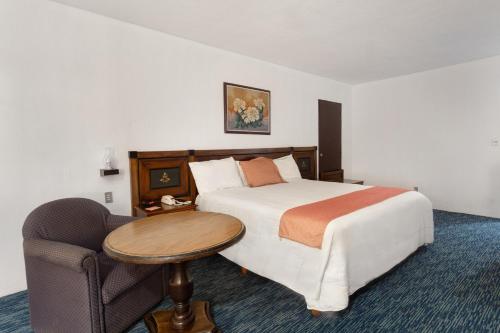 a bedroom with a bed and a table and a chair at Hotel San Jorge in Saltillo