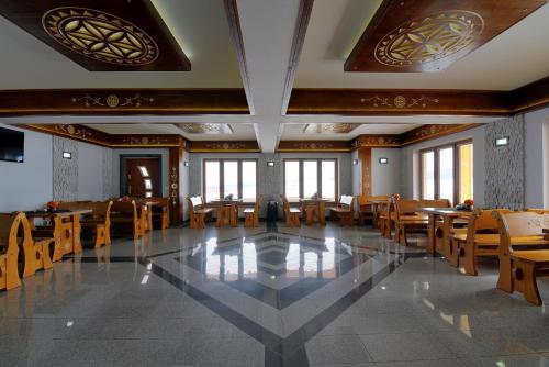 a dining room with tables and chairs and windows at Dom Wczasowy Na Szczycie in Zakopane