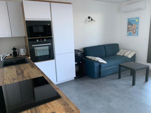 a living room with a blue couch and a kitchen at CAP AU SUD in Hyères