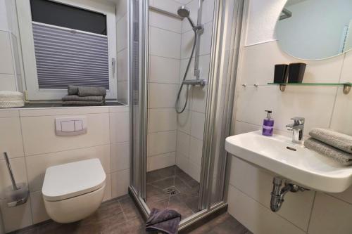 a bathroom with a shower and a toilet and a sink at Ferienkate Norddeich in Norddeich