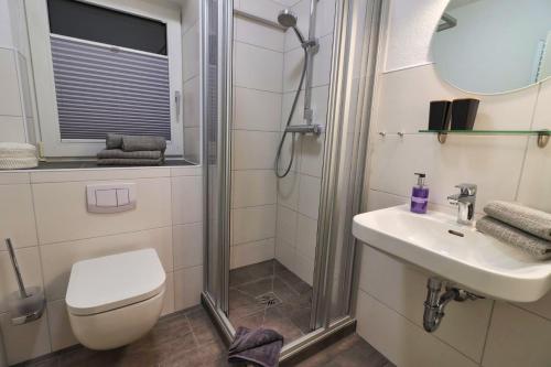 ein Bad mit einer Dusche, einem WC und einem Waschbecken in der Unterkunft Ferienkate Norddeich in Norddeich