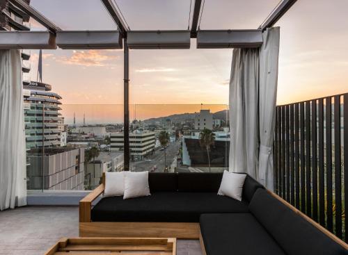 a couch on a balcony with a view of a city at Kimpton Everly Hotel Hollywood, an IHG Hotel in Los Angeles