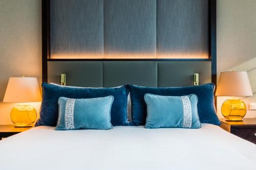 a bedroom with a bed with blue pillows and two lamps at InterContinental Warszawa by IHG in Warsaw