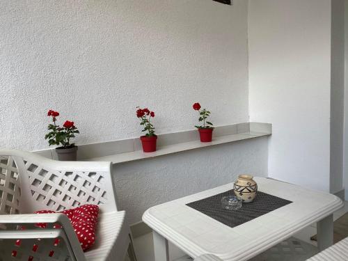 a white table and a white chair with flowers on a shelf at Apartman Travnik in Travnik