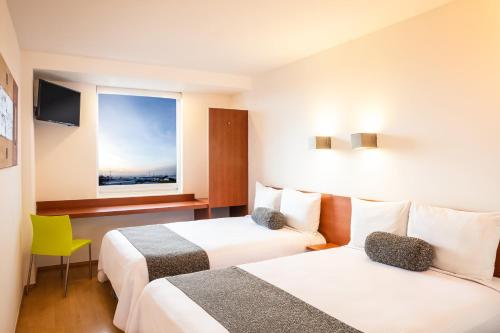 Habitación de hotel con 2 camas y ventana en One Puebla FINSA en Puebla