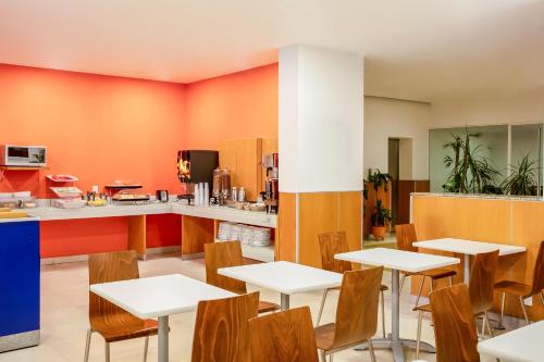 a restaurant with white tables and wooden chairs at One Puebla FINSA in Puebla