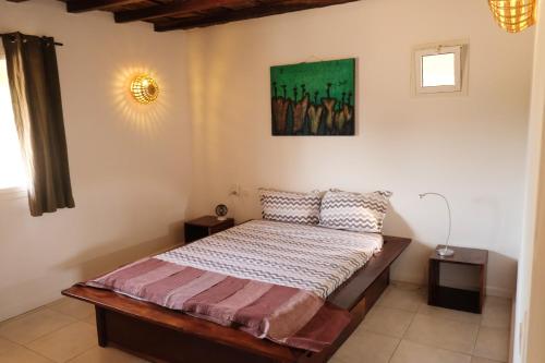 1 dormitorio con 1 cama y una pintura en la pared en 2 bedrooms house at Cap Skirring 50 m away from the beach with sea view furnished terrace and wifi, en Kabrousse