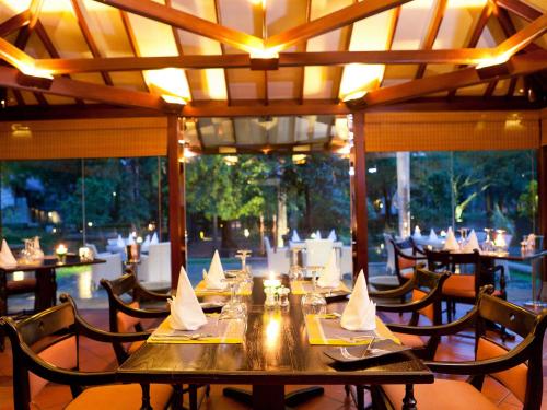 
a dining room table with chairs and tables with umbrellas at Cinnamon Lodge Habarana in Habarana
