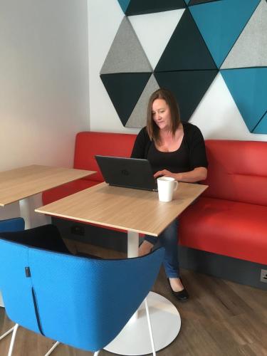 a woman sitting at a table with a laptop at Holiday Inn Express St. Albans - M25, Jct.22 in Saint Albans