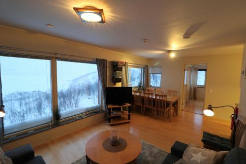 a living room with a couch and a tv and large windows at RIBO Apartment Riksgränsen in Riksgränsen