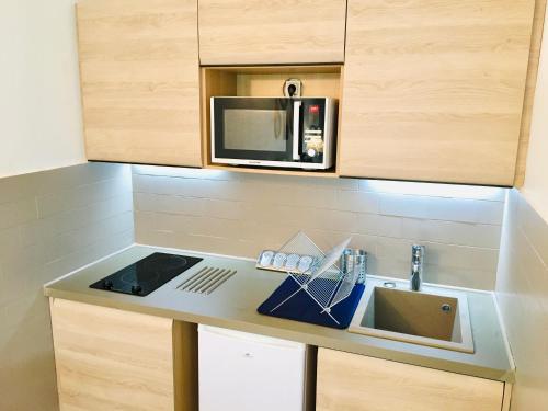 une cuisine avec un évier et un micro-ondes dans l'établissement F2 calme refait à neuf à 5mn de la plage avec parking, au Grau-dʼAgde