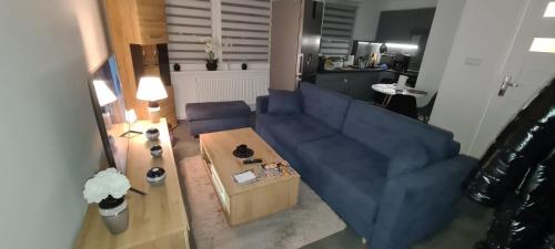 - un salon avec un canapé bleu et une table dans l'établissement Apartment Manhattan, à Tarnowskie Góry