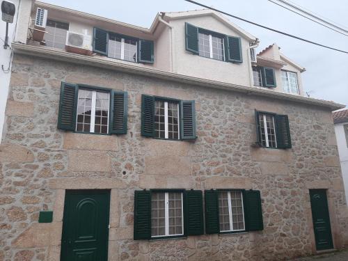 an old building with green shutters on it at casa na aldeia - entre Fundão e Covilhã in Pêro Viseu