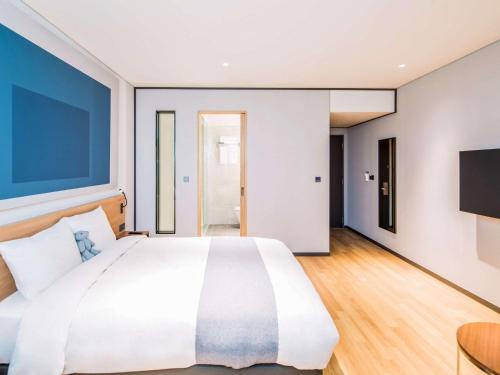 a bedroom with a large white bed and a flat screen tv at Ibis Ambassador Suwon in Suwon