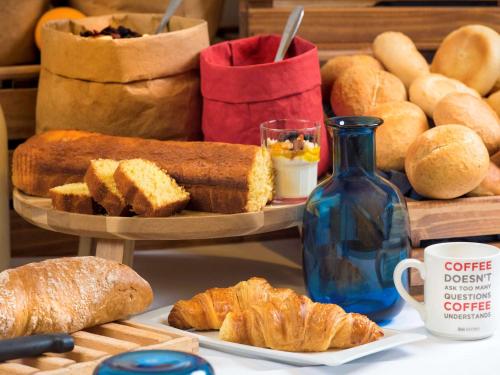 a table with bread and croissants and a blue bottle at ibis budget Hamburg City in Hamburg