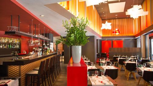 a restaurant with tables and chairs and a vase with flowers at Crowne Plaza Hotel Brugge by IHG in Bruges