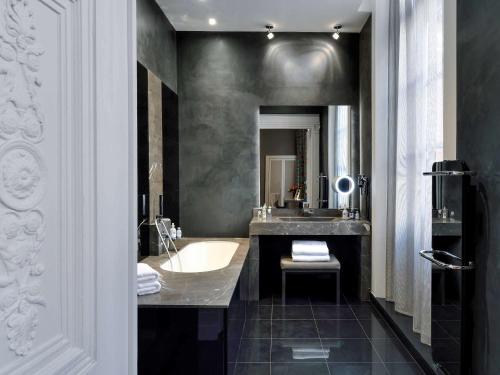 a bathroom with a bath tub and a sink at La Cour des Consuls Hotel & Spa Toulouse - MGallery Collection in Toulouse