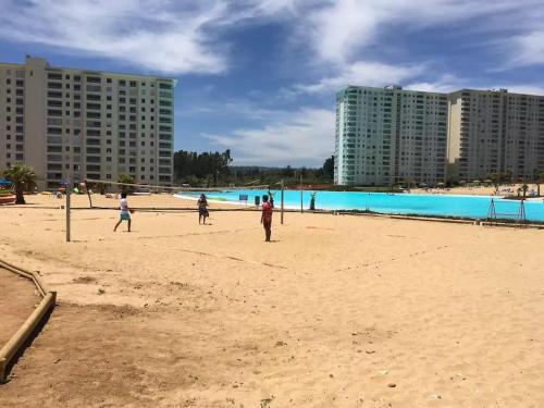 a group of people playing frisbee on the beach at DEPTO LAGUNA BAHIA MARINA in Algarrobo