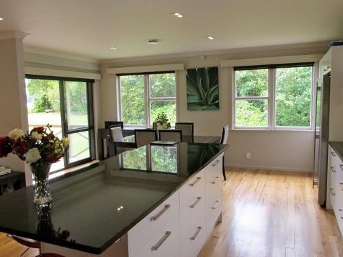 a large kitchen with a counter with chairs and windows at Lake Rotoehu Accommodation - Lake Rotoehu Home in Rotoiti