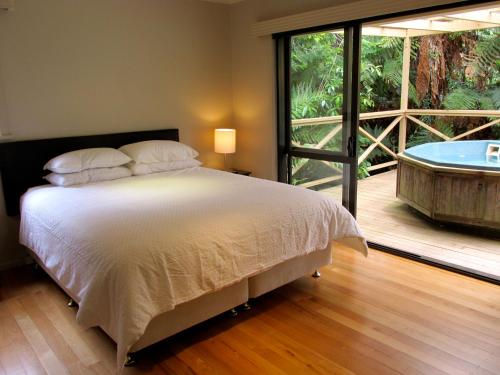 una camera con letto e vasca accanto a un portico di Lake Rotoehu Accommodation - Lake Rotoehu Home a Rotoiti