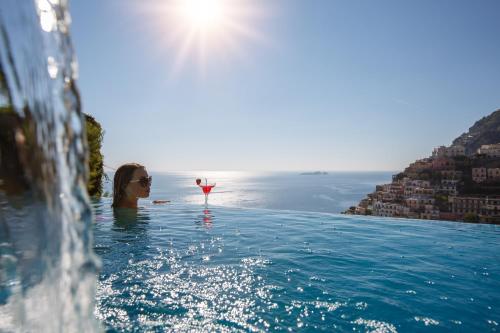 a woman in a swimming pool with a glass of wine at Villa Fiorentino in Positano