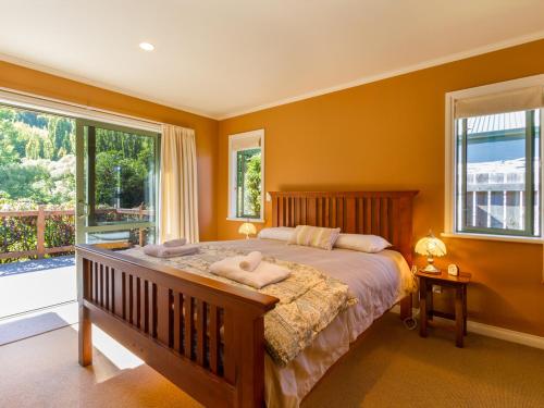 a bedroom with a large bed with two windows at Sawmillers Retreat - Arrowtown Holiday Home in Arrowtown