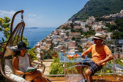 a man and woman sitting at a table with a view of a city at Villa Fiorentino in Positano