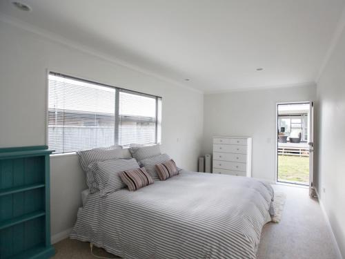 - une chambre avec un lit avec deux oreillers et une fenêtre dans l'établissement Waikanae Retreat - Waikanae Beach Holiday Home, à Waikanae
