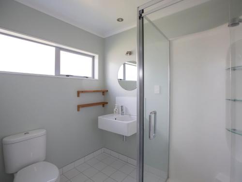 a bathroom with a shower and a toilet and a sink at Waikanae Retreat - Waikanae Beach Holiday Home in Waikanae