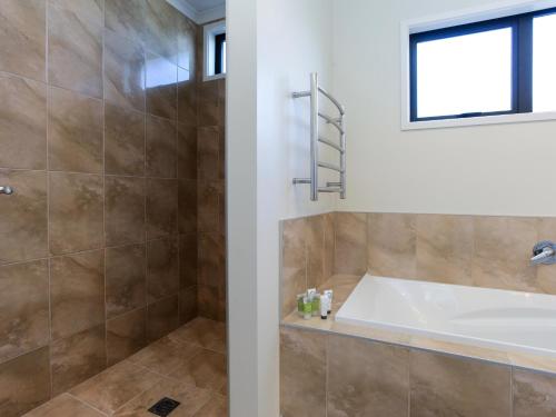 La salle de bains est pourvue d'une baignoire et d'une cabine de douche. dans l'établissement Te Awa Napier Treasure - Napier Holiday Home, à Napier