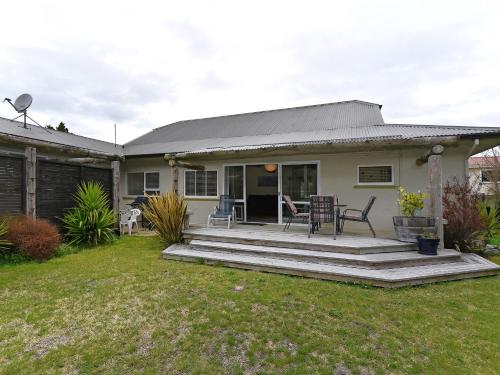 a house with a deck with a table and chairs at Vista Lagoon - Kaiteriteri Holiday Unit in Kaiteriteri