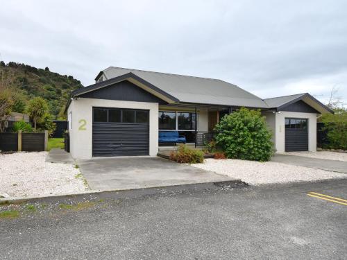 a house with two garage doors in a driveway at Vista Lagoon - Kaiteriteri Holiday Unit in Kaiteriteri