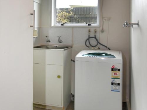 a small bathroom with a sink and a washing machine at Blue Lagoon - Kaiteriteri Holiday Unit in Kaiteriteri