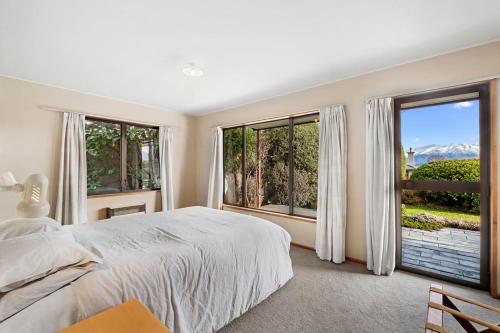 a bedroom with a large bed and large windows at Sycamore Place - Wanaka Holiday Home in Wanaka