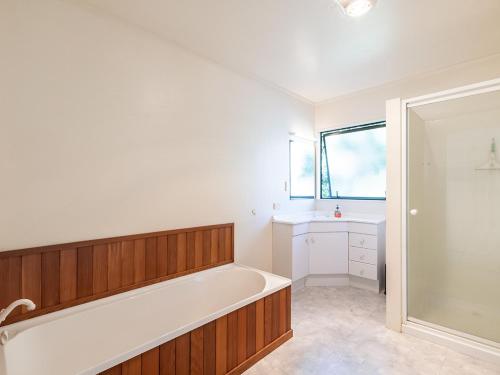 a bathroom with a bath tub and a sink at Kawau Vista - Snells Beach Holiday Home in Snells Beach