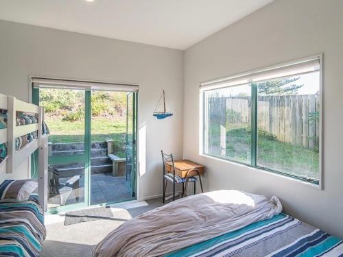 Schlafzimmer mit einem Bett, einem Fenster und einem Schreibtisch in der Unterkunft Beachfront Getaway - Waikanae Beach Holiday Home in Waikanae