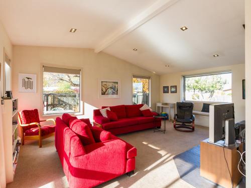 a living room with red couches and a tv at Brow Peak View - Arrowtown Holiday Home in Arrowtown