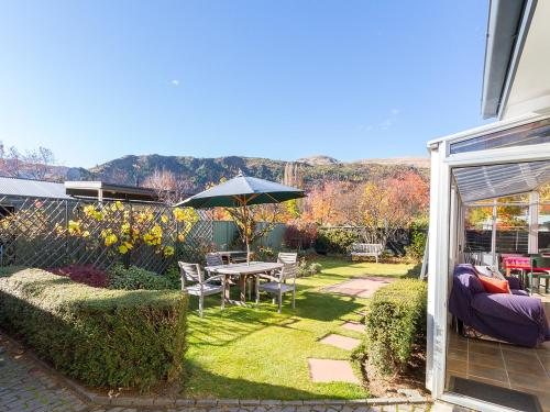 a garden with a table and an umbrella at Brow Peak View - Arrowtown Holiday Home in Arrowtown