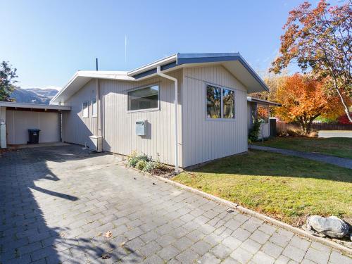 a white house with a driveway in front of it at Brow Peak View - Arrowtown Holiday Home in Arrowtown