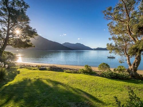 a view of a beach with a boat in the water at Sounds Magic - Moetapu Bay Bach in Ohingaroa