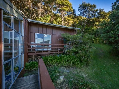 a house with a wooden deck and a balcony at Sounds Magic - Moetapu Bay Bach in Ohingaroa