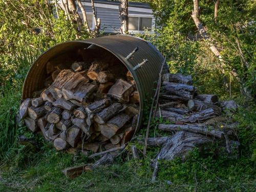 a barrel full of fire wood in the grass at Sounds Magic - Moetapu Bay Bach in Ohingaroa