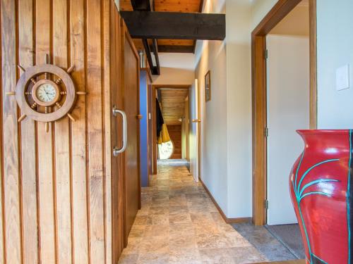 a hallway with wooden walls and a clock on the wall at Tasman Hideaway - Marahau Holiday Home in Marahau