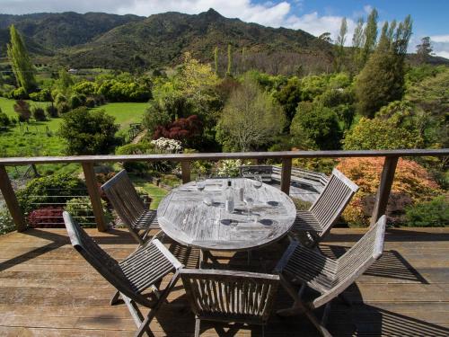 a glass table and chairs on a deck with a view at Tasman Hideaway - Marahau Holiday Home in Marahau