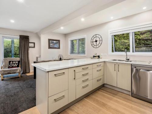 an empty kitchen with white cabinets and a sink at The Hillvue with Spa - Arrowtown Holiday Home in Arrowtown