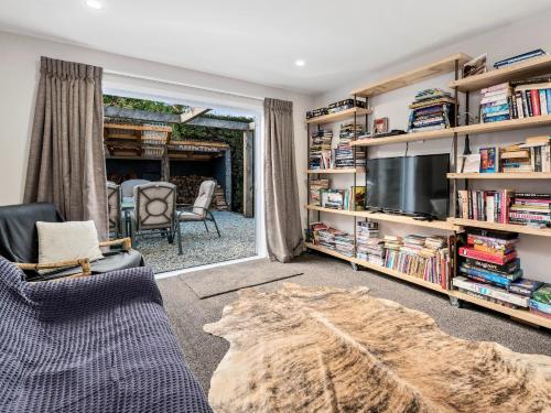 a living room with a tv and book shelves at The Hillvue with Spa - Arrowtown Holiday Home in Arrowtown