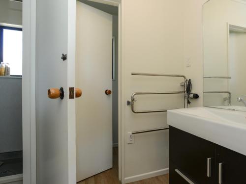 baño con puerta blanca y lavamanos en Bach 112 - Waimarama Holiday Home en Waimarama