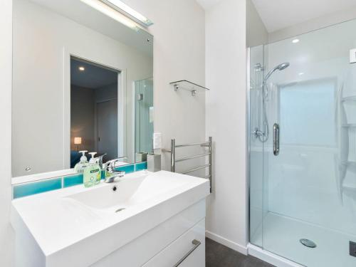a white bathroom with a sink and a shower at Pisa Oasis - Cromwell Holiday Home in Cromwell